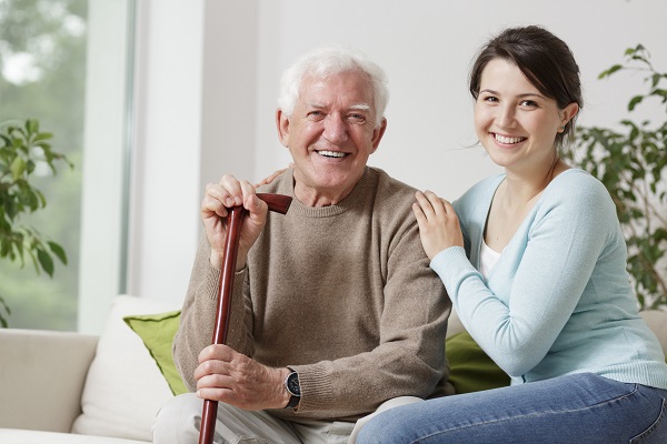 Woman seated next to an elderly man with a walking stick