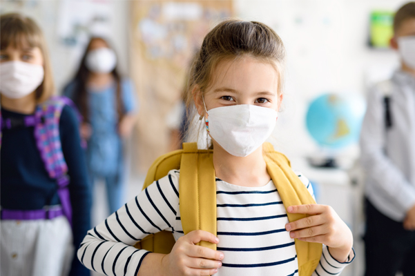 Little girl wearing a mask in school